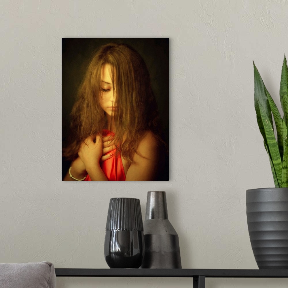 A modern room featuring A woman with her hair in her face holding up a red cloth to her chest.