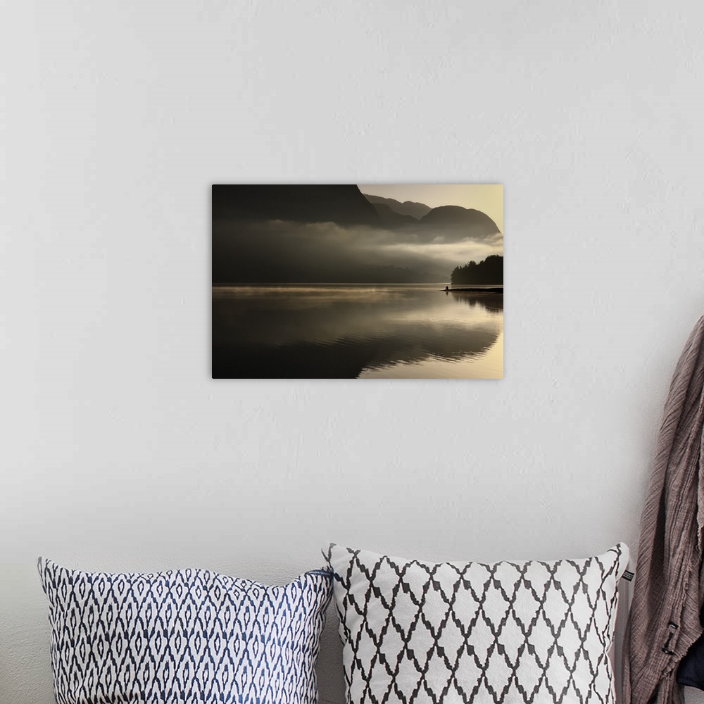 A bohemian room featuring Distant figure sitting on the banks of a lake with misty clouds at sunset.