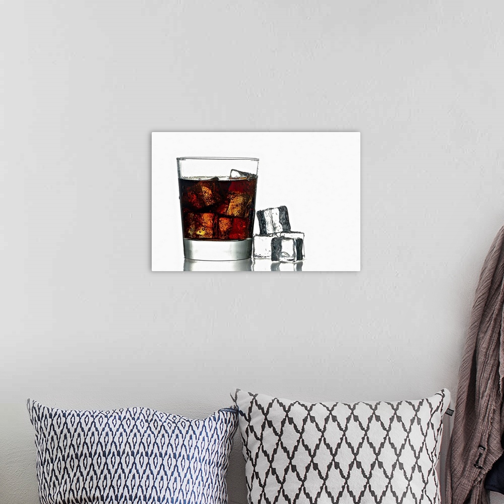 A bohemian room featuring A photo of a glass of fresh icy cold cola with ice cubes next to.