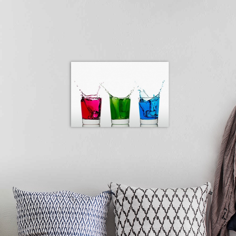 A bohemian room featuring Ice cubes falling into three glasses with different colored liquid
