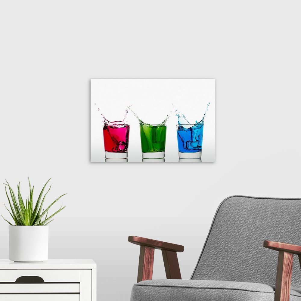 A modern room featuring Ice cubes falling into three glasses with different colored liquid
