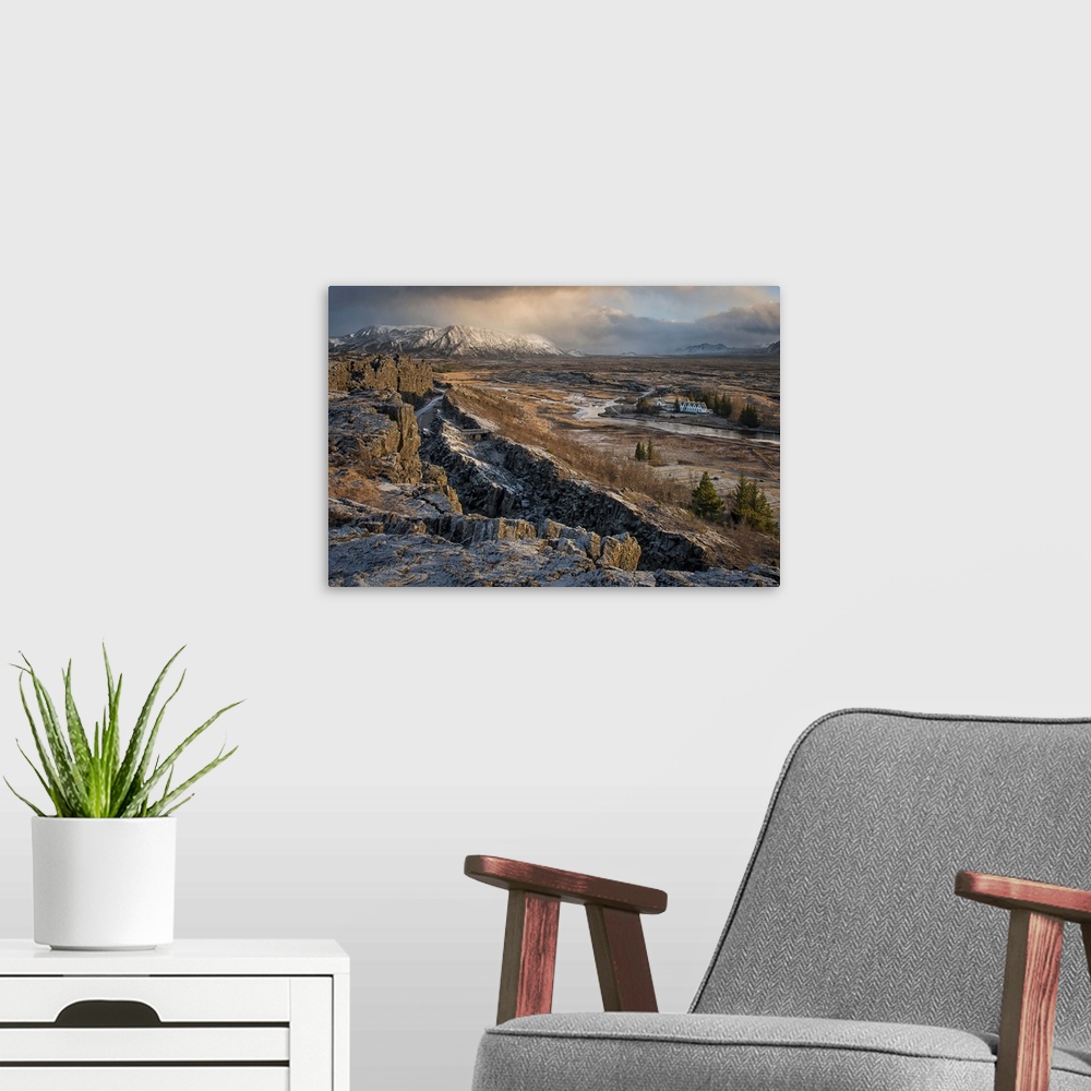 A modern room featuring A small village can be seen in the distance of this desolate looking Icelandic rift valley.