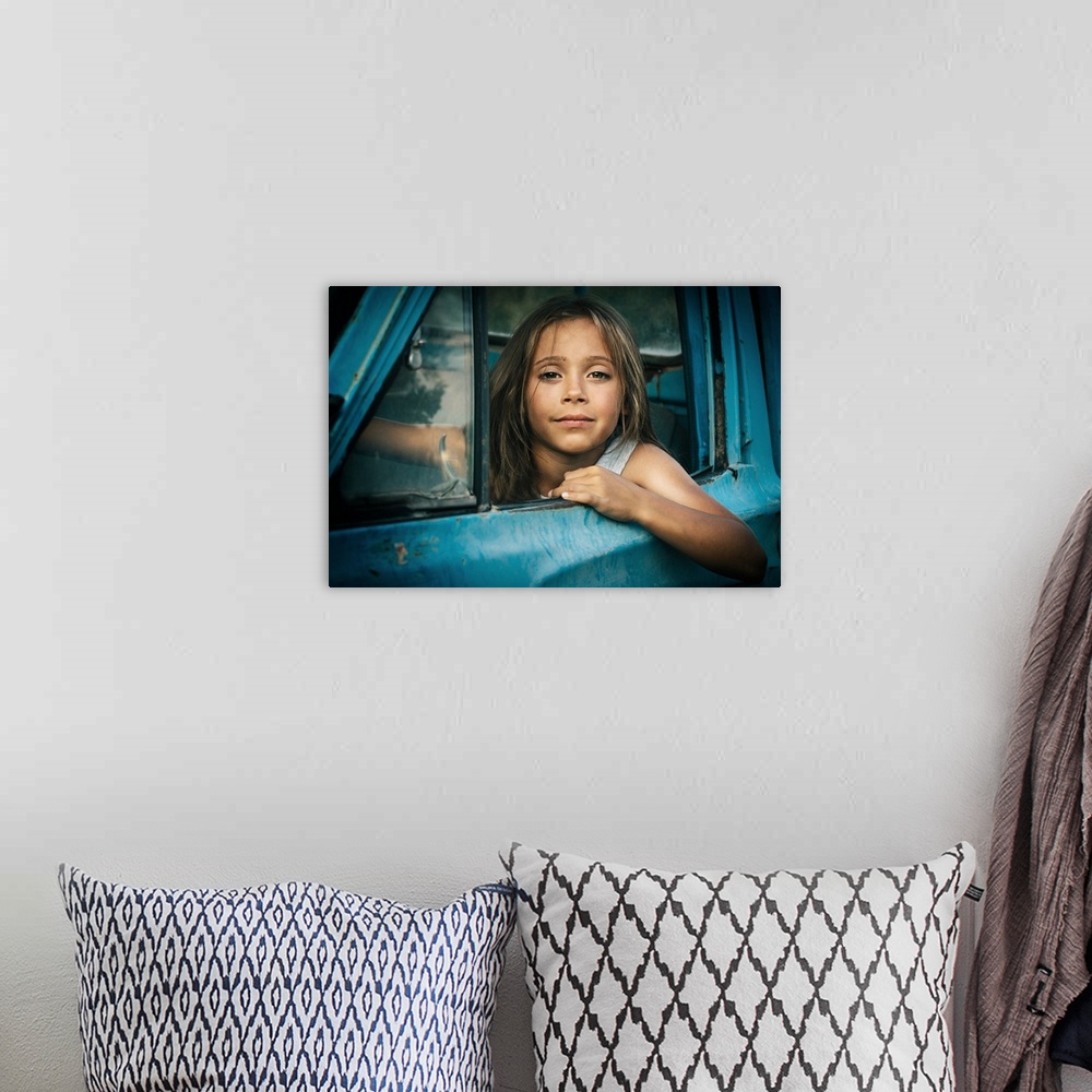 A bohemian room featuring Portrait of a young girl leaning out the window of a blue car.