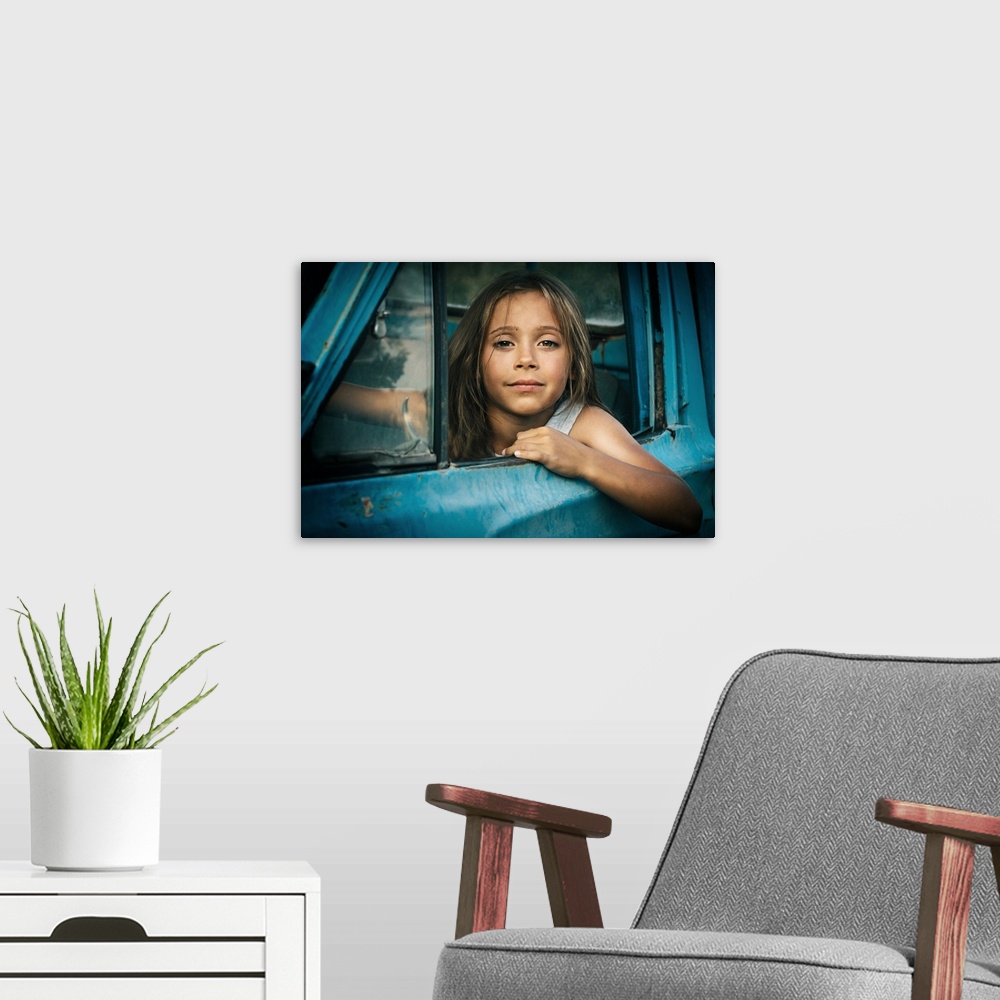A modern room featuring Portrait of a young girl leaning out the window of a blue car.