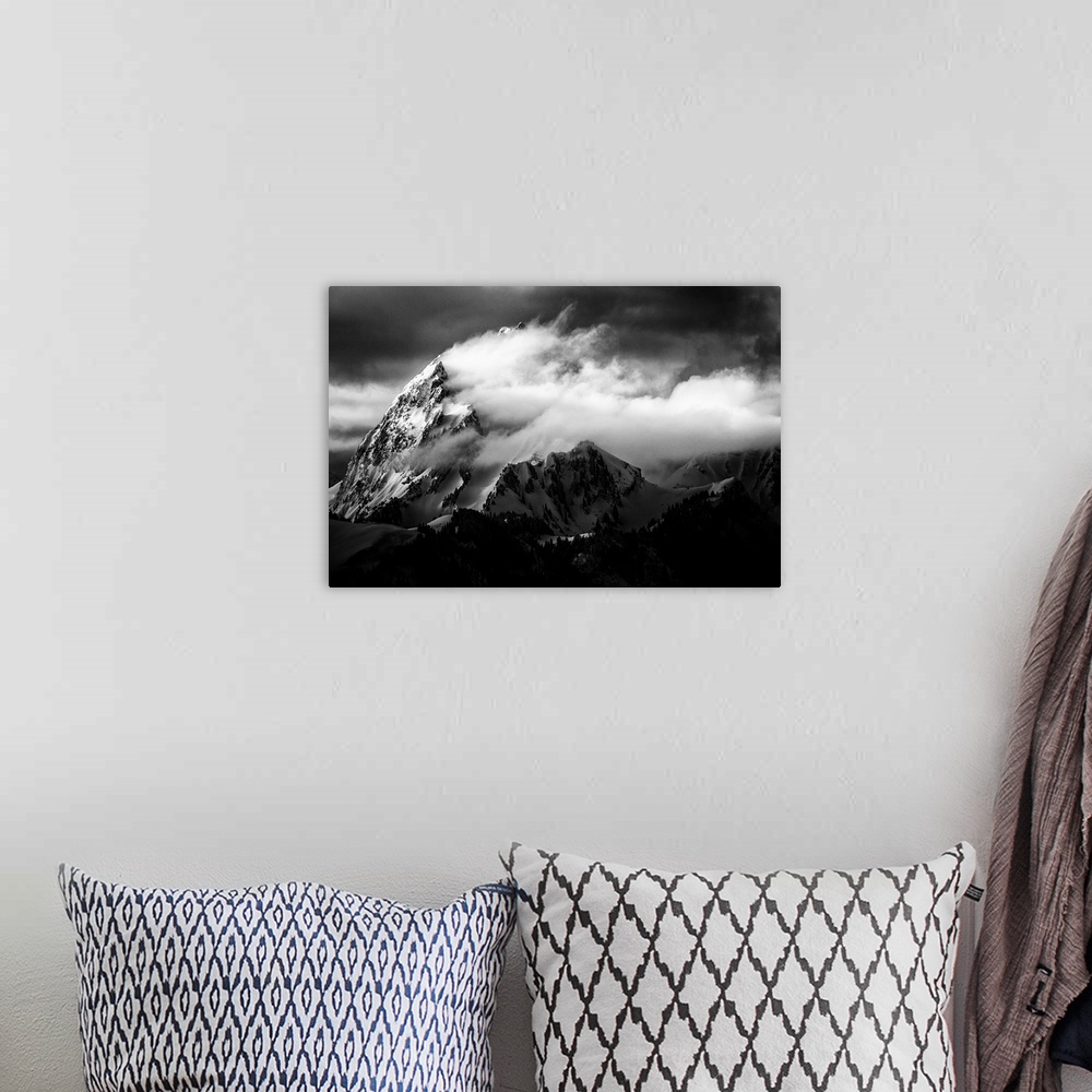 A bohemian room featuring A dramatic black and white photograph of a jagged mountain peak with clouds blown around it.