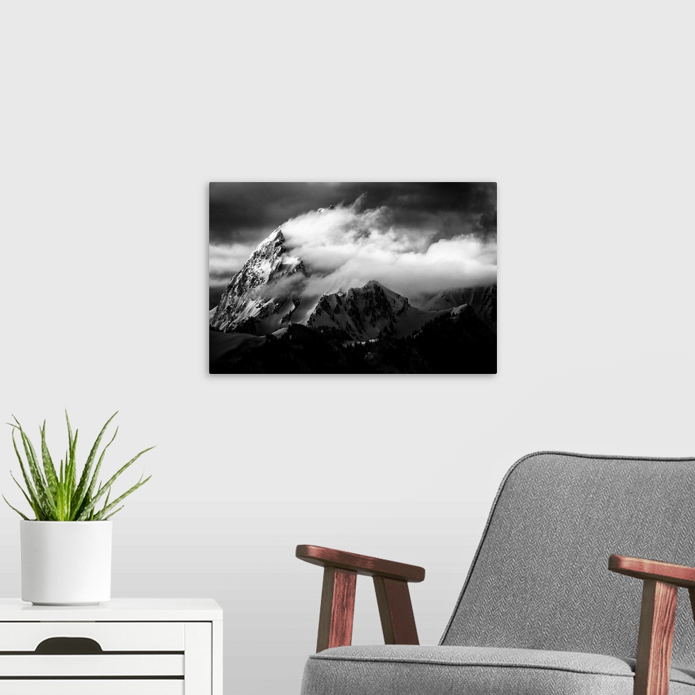A modern room featuring A dramatic black and white photograph of a jagged mountain peak with clouds blown around it.