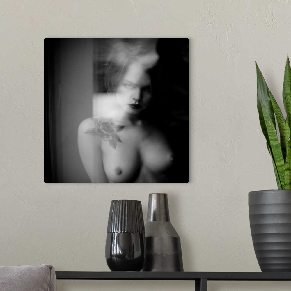 A modern room featuring Soft focus black and white portrait of a nude woman from the chest up with a rose tattoo.