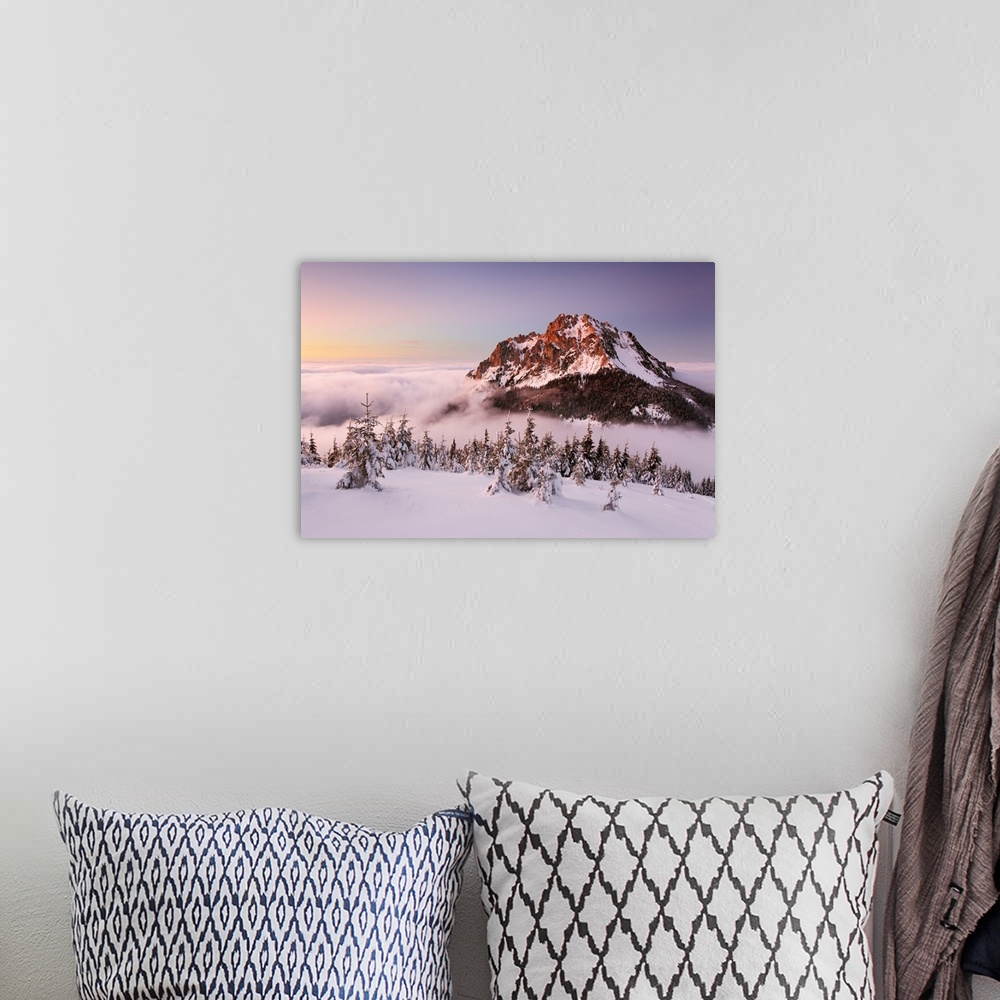 A bohemian room featuring The snowy peak of a mountain in the winter, rising out of the clouds, Slovakia.