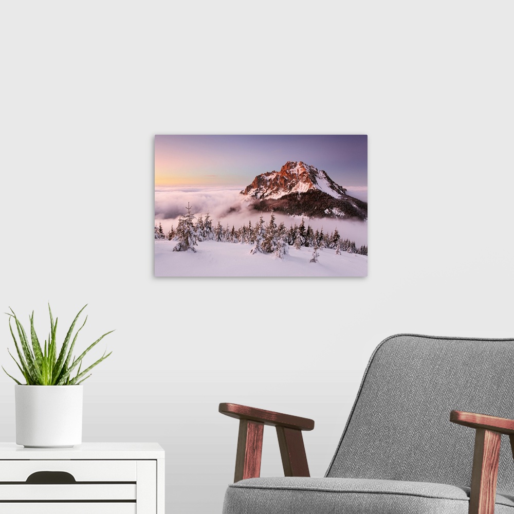 A modern room featuring The snowy peak of a mountain in the winter, rising out of the clouds, Slovakia.