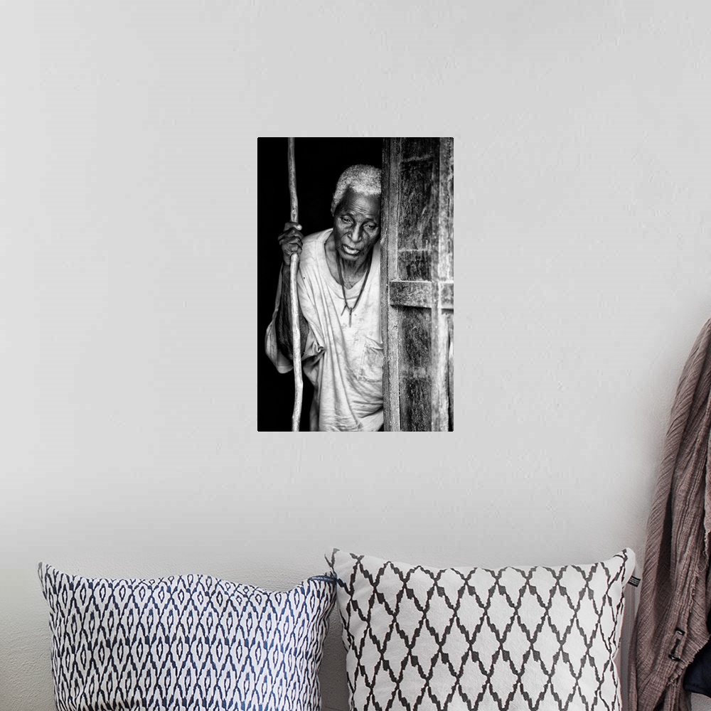 A bohemian room featuring Black and white portrait of an elderly person with a staff in a doorway.