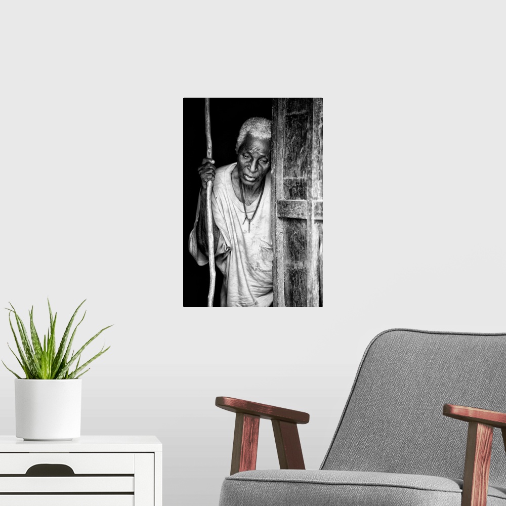 A modern room featuring Black and white portrait of an elderly person with a staff in a doorway.