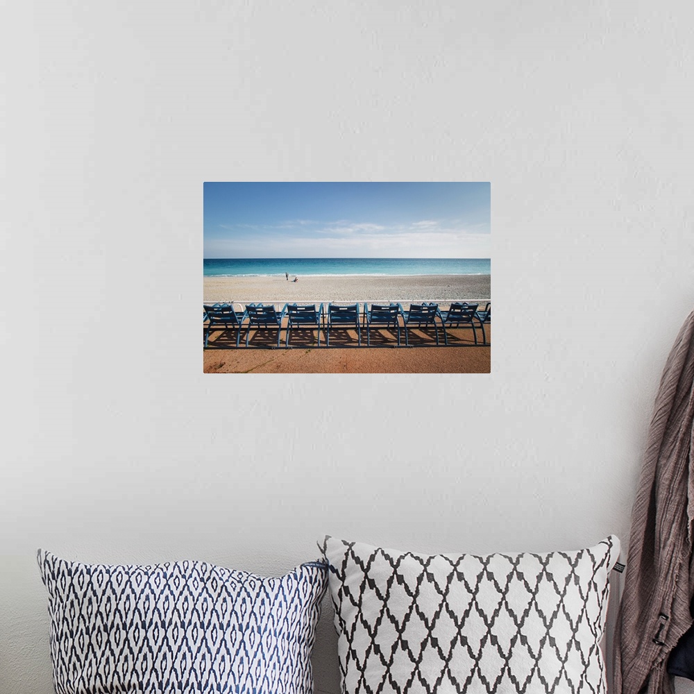 A bohemian room featuring Landscape photograph of the ocean shore with a row of blue beach chairs.