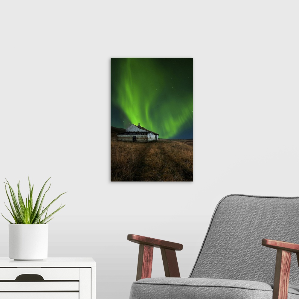 A modern room featuring An abandoned house in a field in Iceland, with a brilliant northern lights display in the skies a...