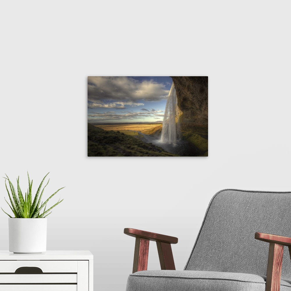 A modern room featuring The Seljalandsfoss waterfall in Iceland, overlooking a wide open plain.