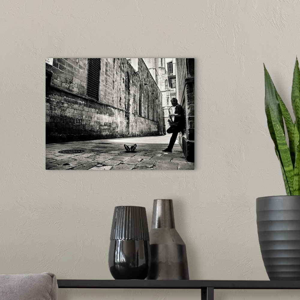 A modern room featuring A black and white photograph of a person playing a saxophone in an alley.