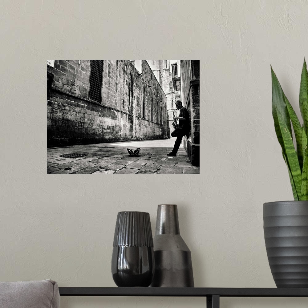 A modern room featuring A black and white photograph of a person playing a saxophone in an alley.