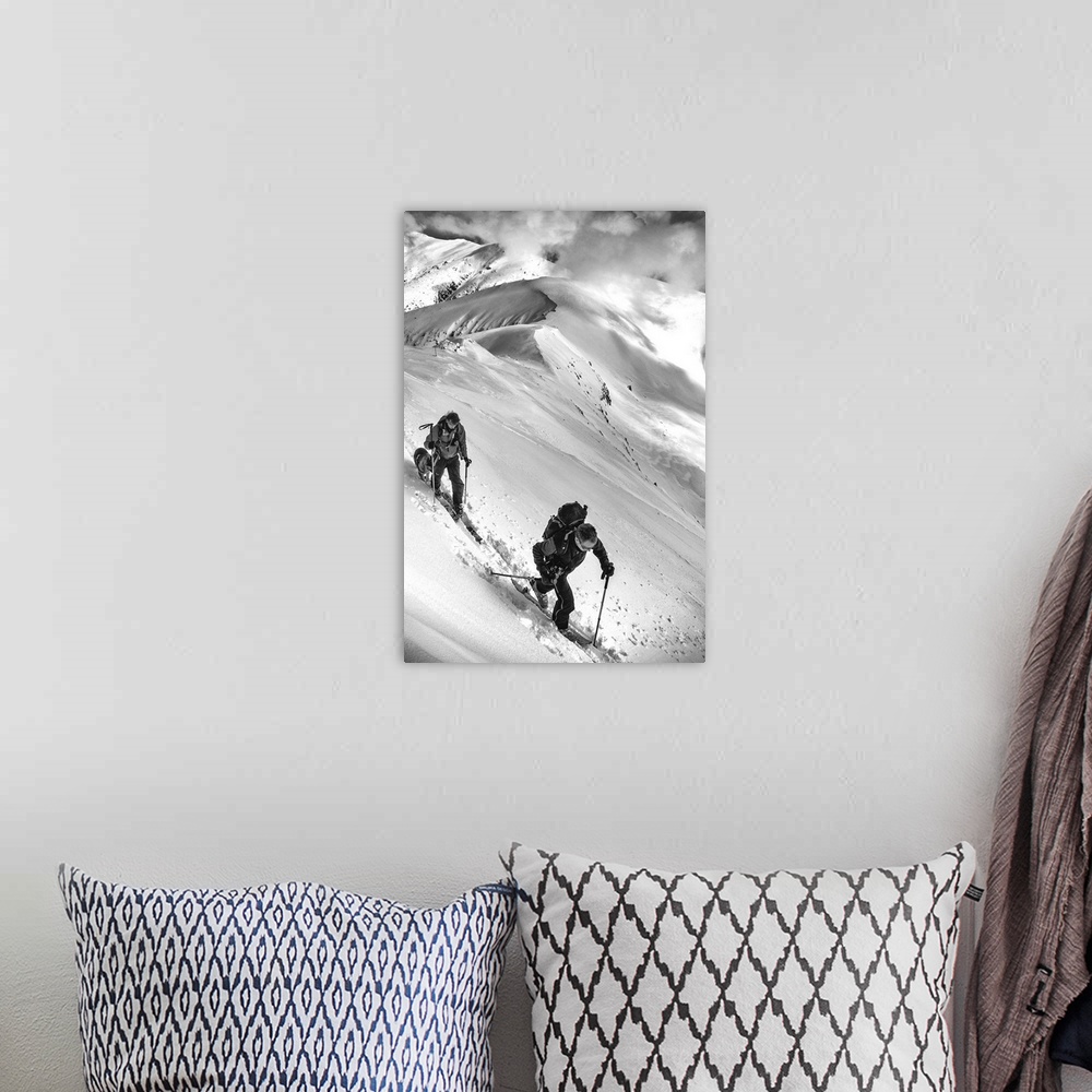 A bohemian room featuring Two people and a dog trek through the snow on an alpine mountaintop.