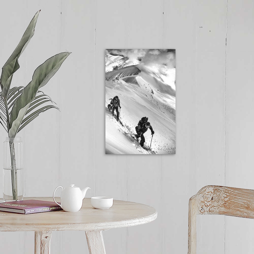 A farmhouse room featuring Two people and a dog trek through the snow on an alpine mountaintop.