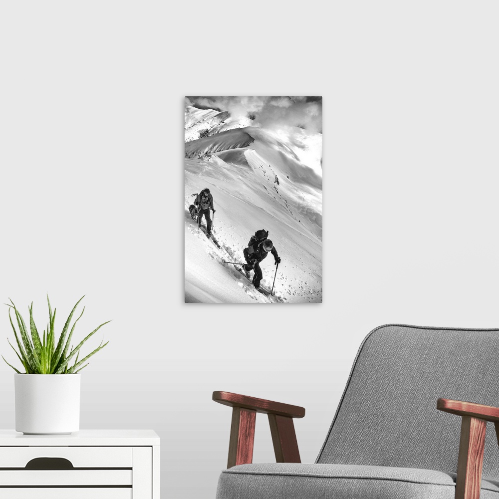 A modern room featuring Two people and a dog trek through the snow on an alpine mountaintop.