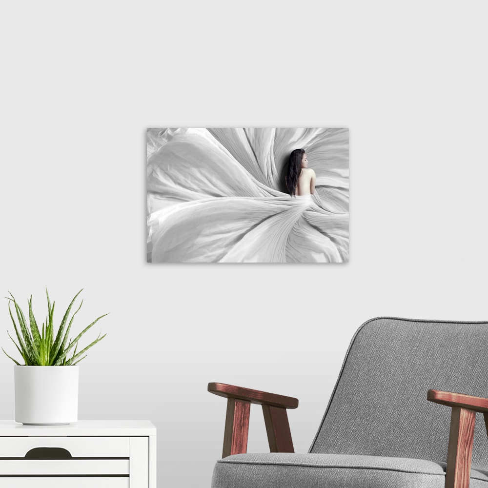 A modern room featuring A woman wrapped in a white sheet which flows around her, resembling a flower.