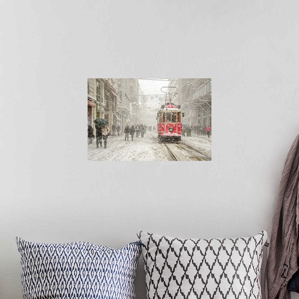 A bohemian room featuring A snowstorm raining down on a city with a red street car in the street.