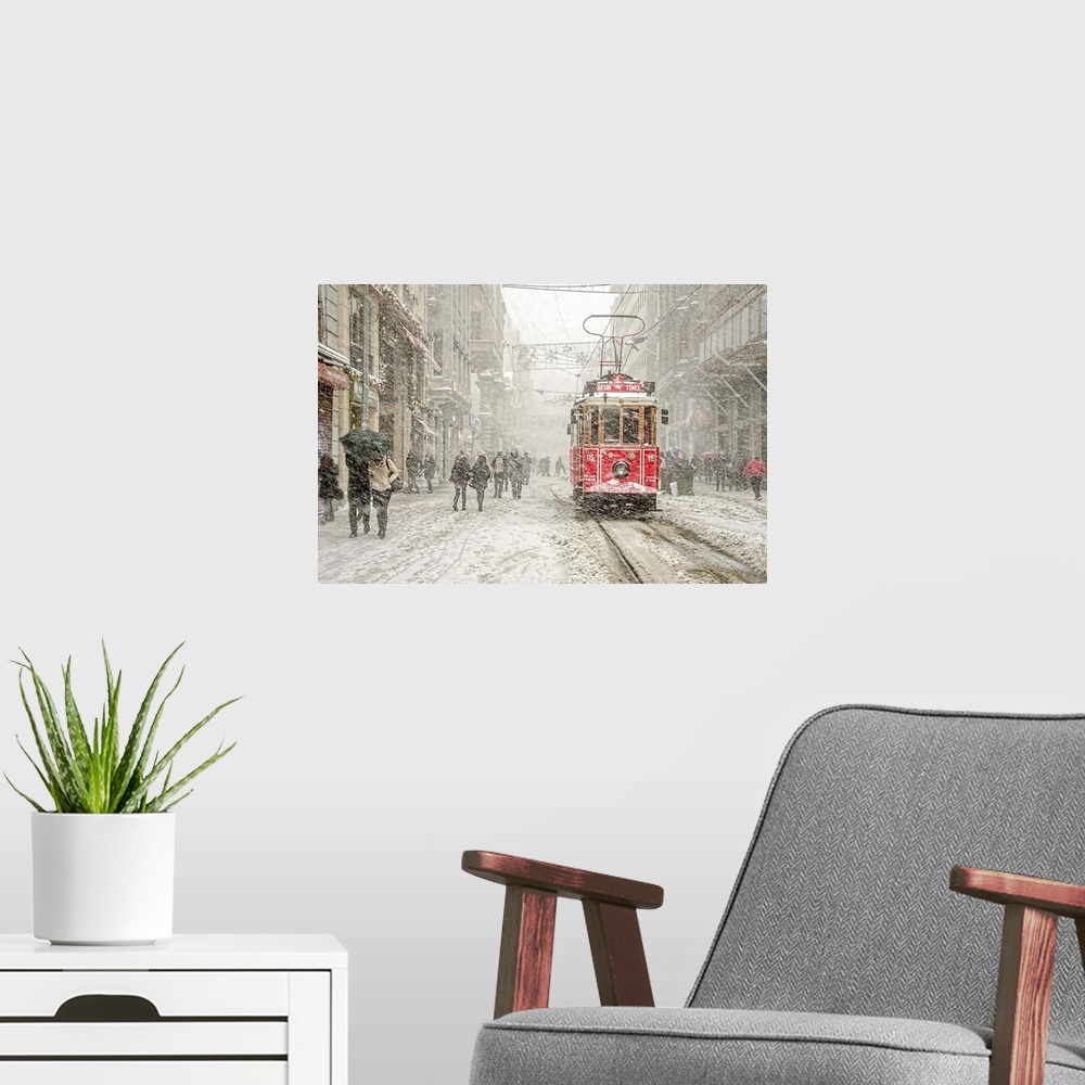 A modern room featuring A snowstorm raining down on a city with a red street car in the street.
