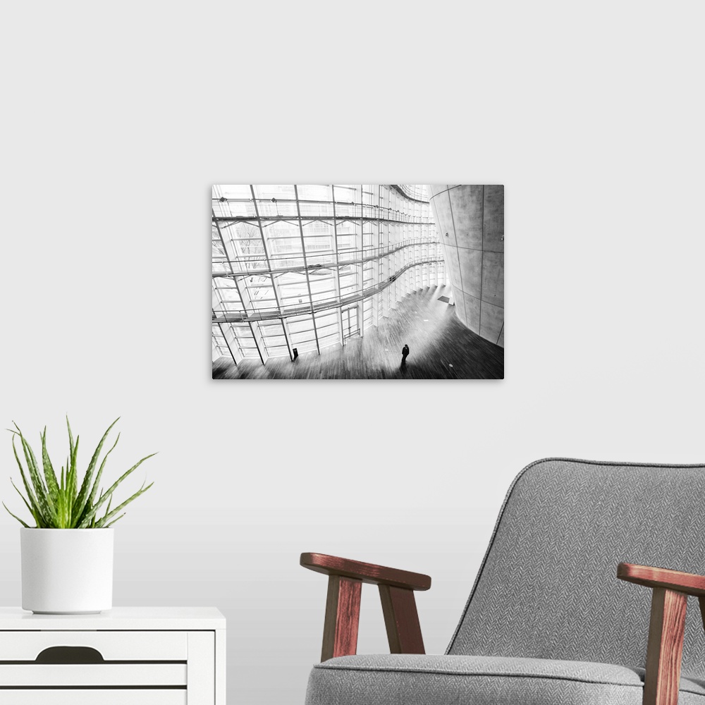 A modern room featuring Black and white image of curving architecture, with a lone figure.