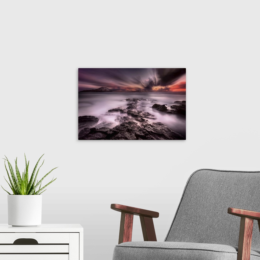 A modern room featuring A dramatic view of a rocky coastline looking out to the sea under a blanket of intense clouds.