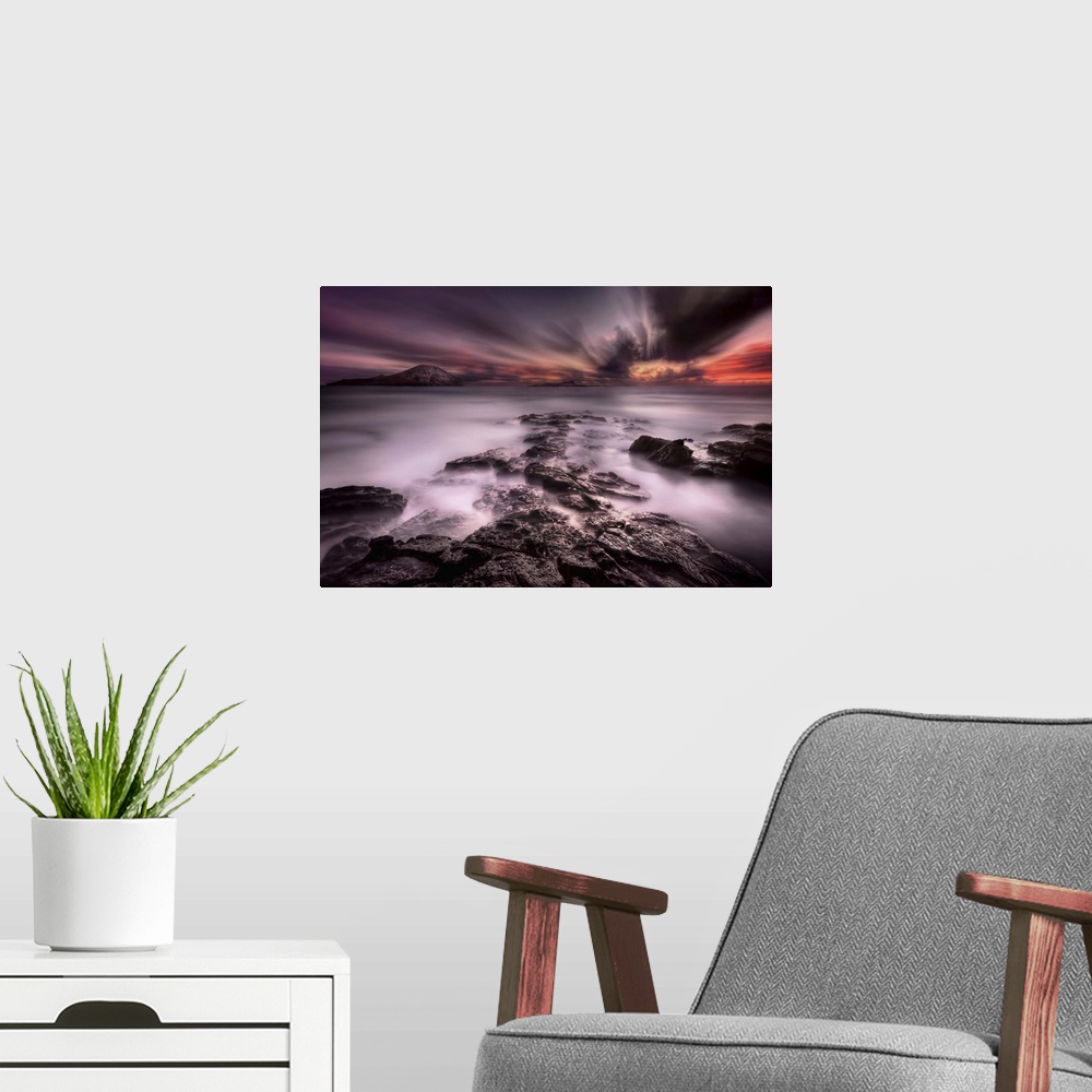 A modern room featuring A dramatic view of a rocky coastline looking out to the sea under a blanket of intense clouds.
