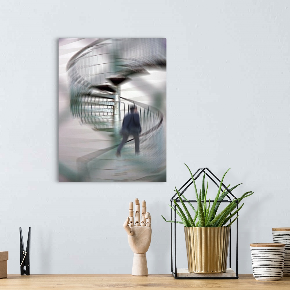 A bohemian room featuring A blurred motion photo of a businessman talking up a spiral staircase.