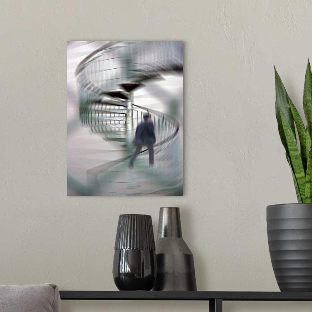 A modern room featuring A blurred motion photo of a businessman talking up a spiral staircase.