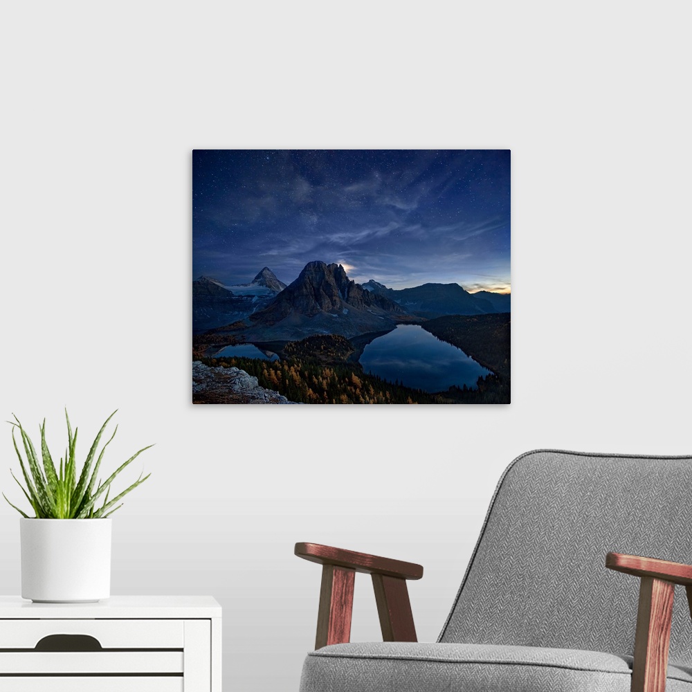 A modern room featuring Mount Assiniboine in the Canadian Rockies at night, under a starry sky.
