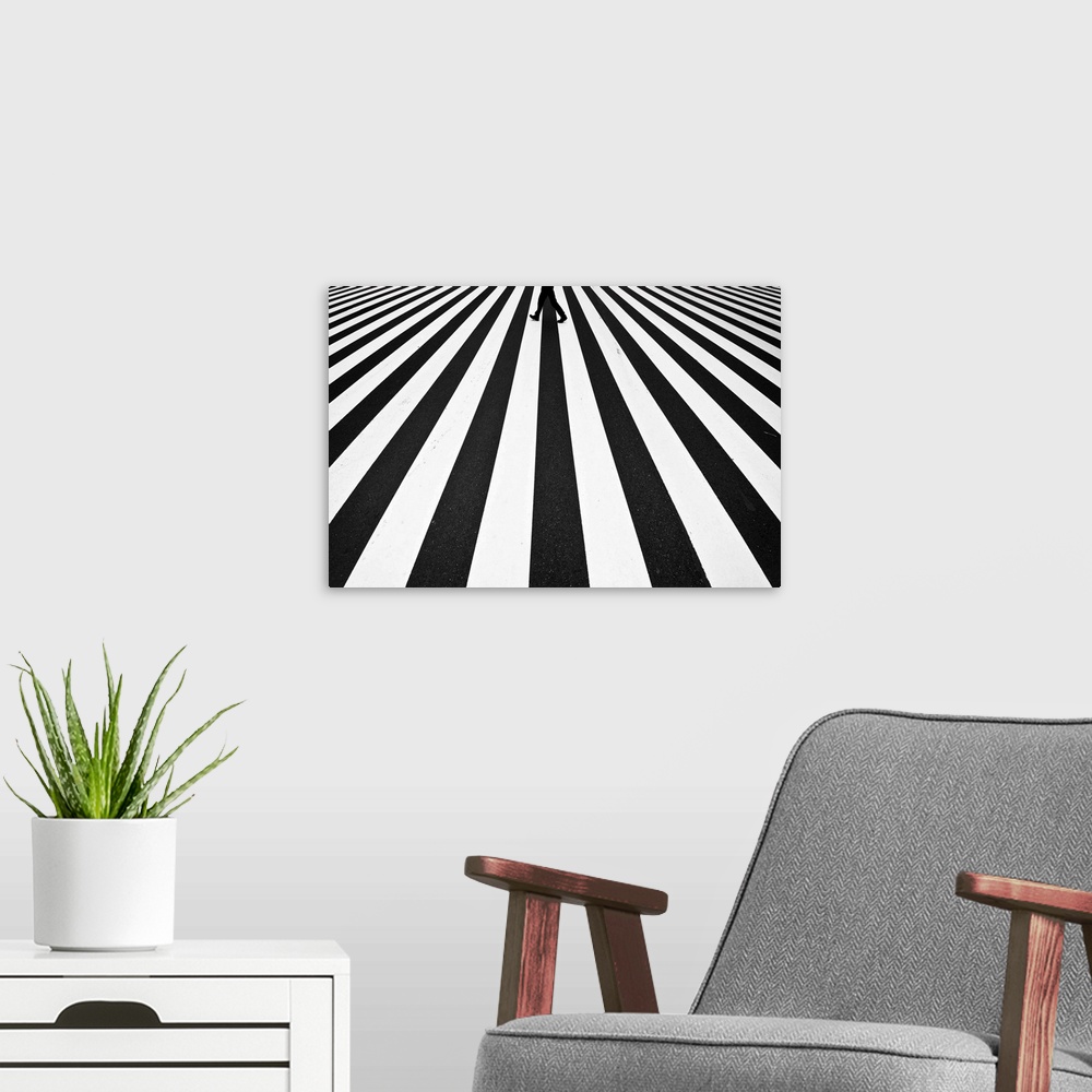 A modern room featuring A pattern created by a zebra crossing in the street is broken by a figure walking across.