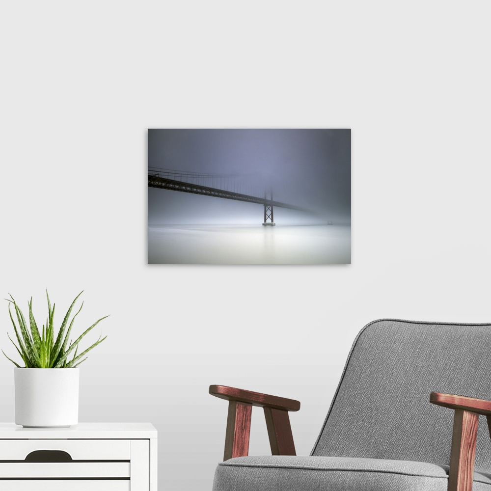 A modern room featuring The cables and towers of the Golden Gate Bridge partially obscured by heavy fog.