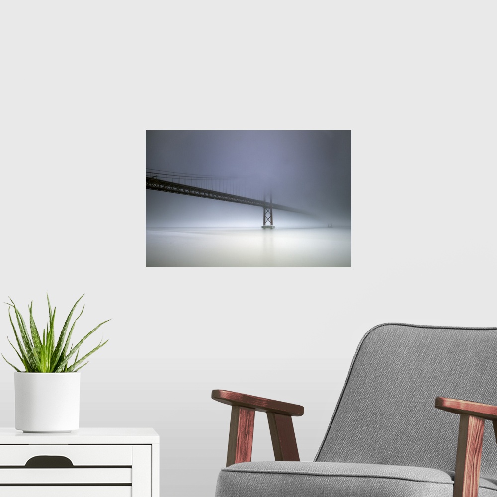 A modern room featuring The cables and towers of the Golden Gate Bridge partially obscured by heavy fog.