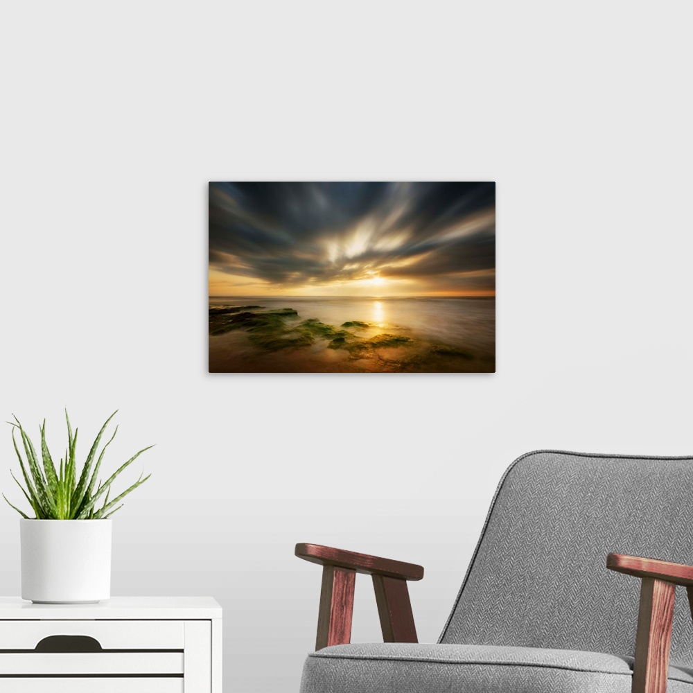 A modern room featuring Dramatic clouds at sunrise over the coast of Spain.