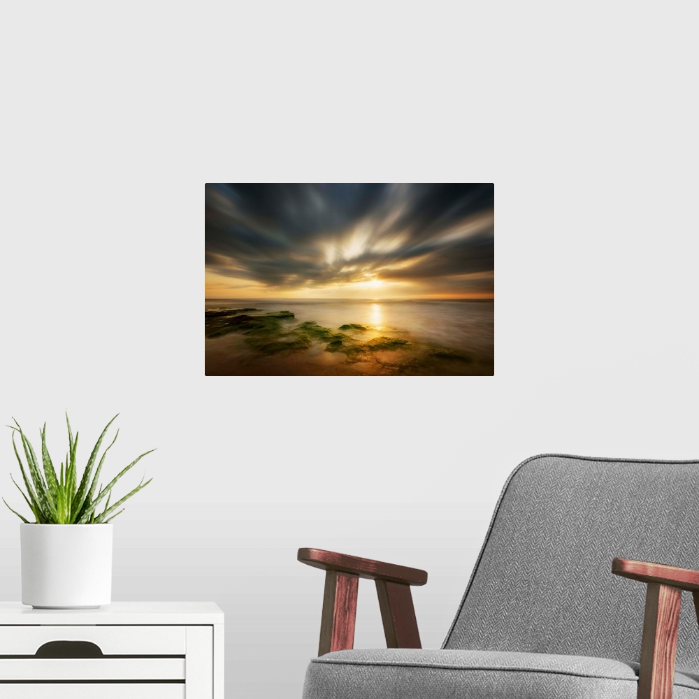 A modern room featuring Dramatic clouds at sunrise over the coast of Spain.