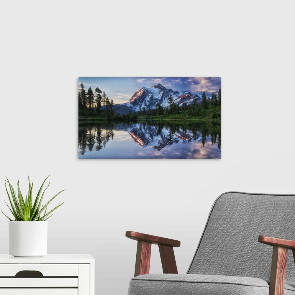 A modern room featuring Mount Shuksan in Washington mirrored in the lake below at dawn.