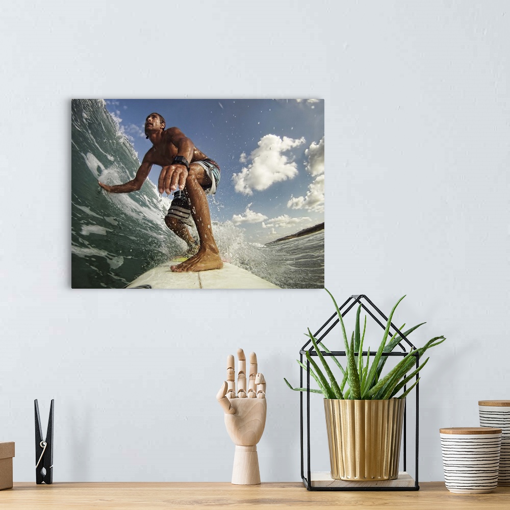 A bohemian room featuring A man on a surfboard rides a wave and touches the water with his outstretched hand on a sunny day.