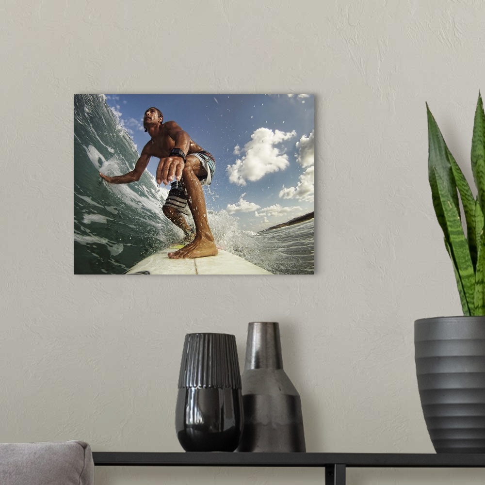 A modern room featuring A man on a surfboard rides a wave and touches the water with his outstretched hand on a sunny day.