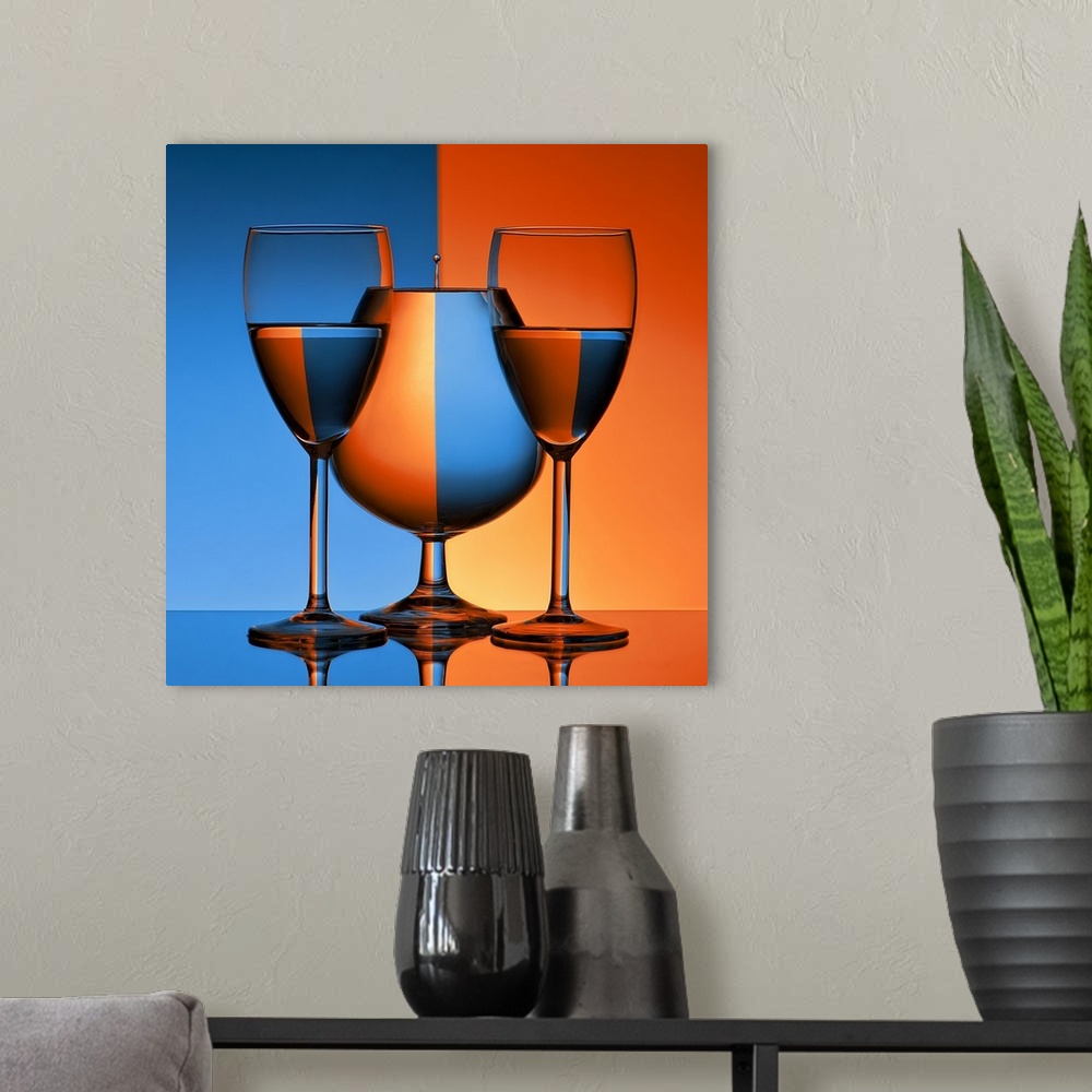 A modern room featuring Conceptual image of three glasses reflecting mirror images of a blue and orange background.