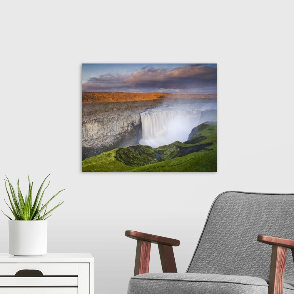 A modern room featuring A large waterfall in Iceland in a colorful landscape at sunset.