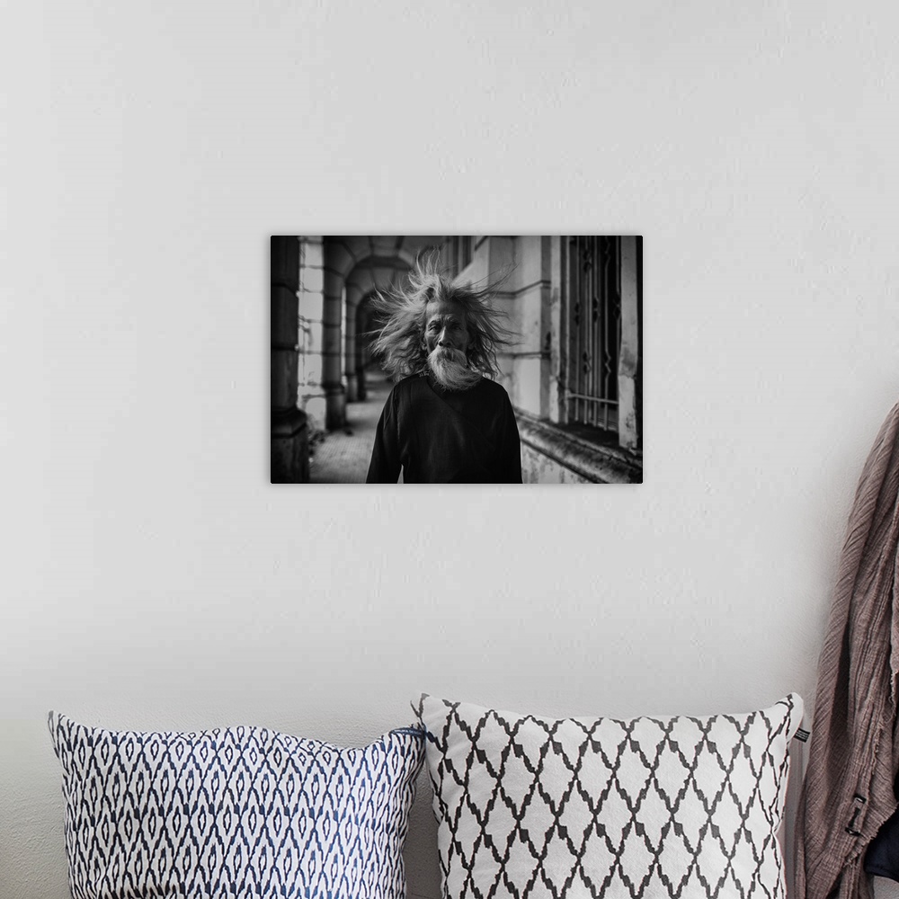 A bohemian room featuring A portrait of an old man with wind blown hair.