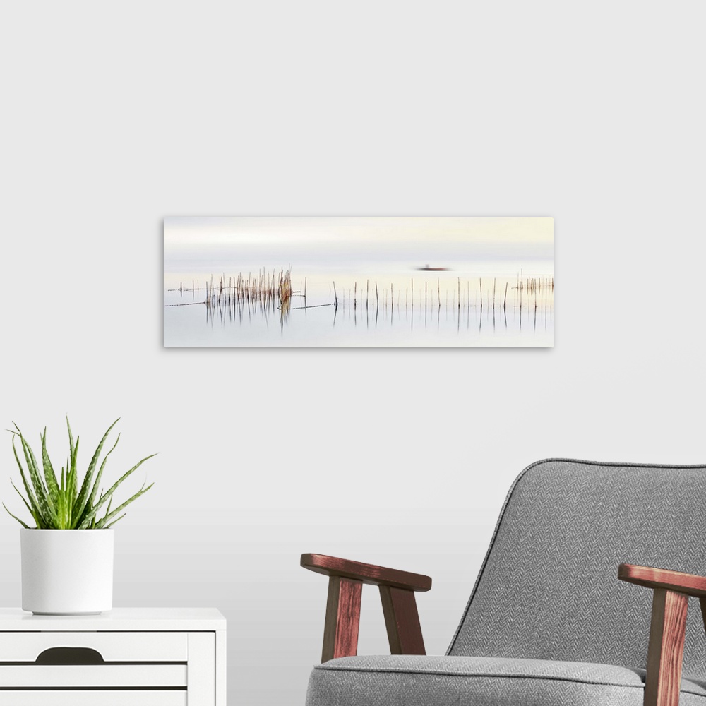 A modern room featuring Long exposure of reeds in a pond with a  boat traveling along the water.