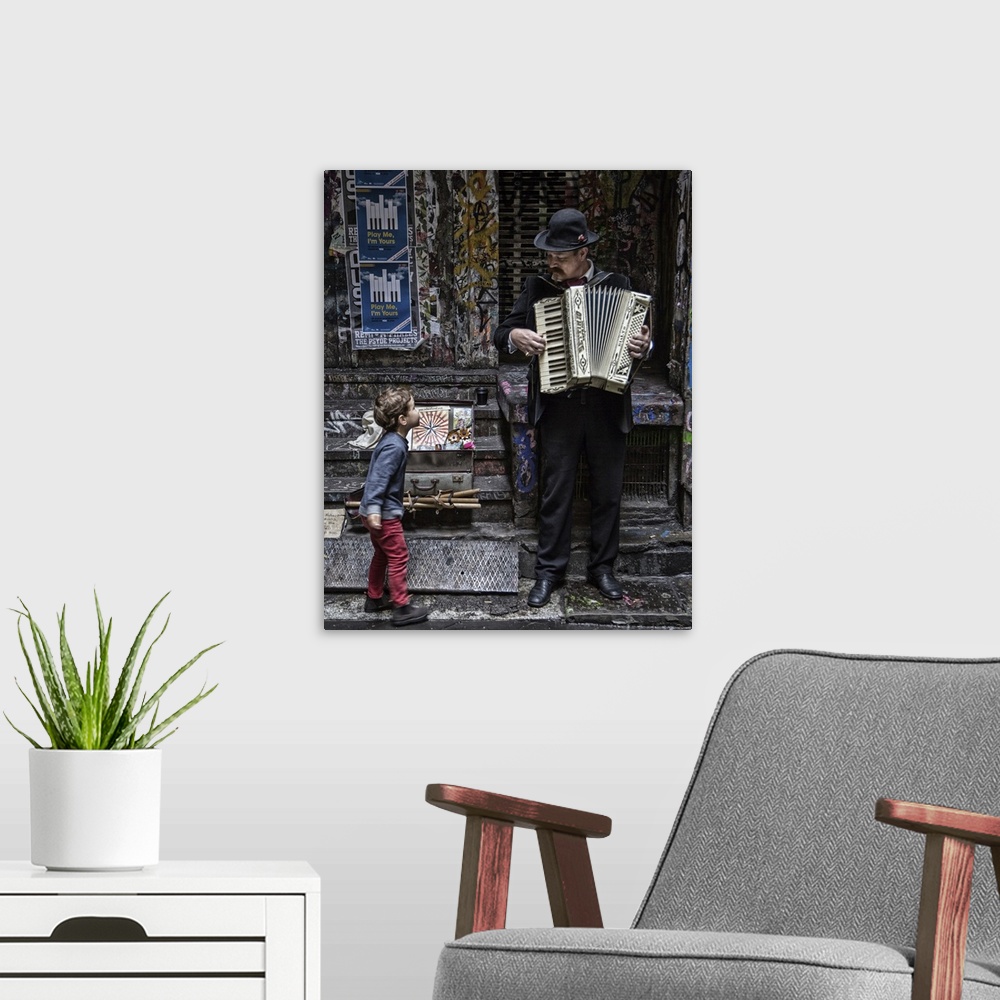 A modern room featuring A little boy stops on a sidewalk to watch a musician play an accordion.