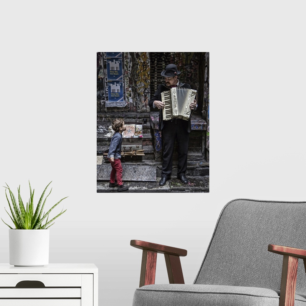 A modern room featuring A little boy stops on a sidewalk to watch a musician play an accordion.