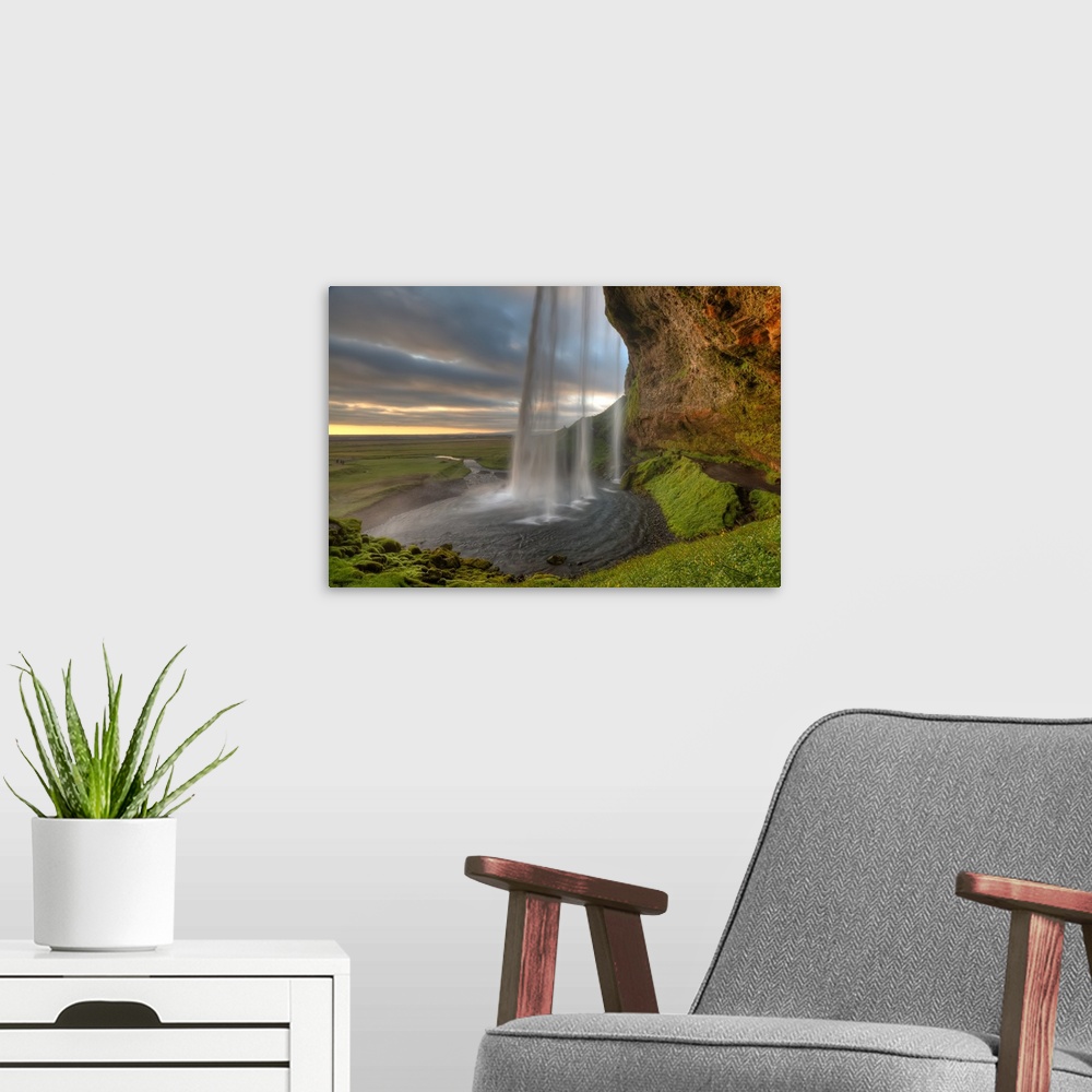 A modern room featuring The Seljalandsfoss Waterfall in Iceland and the wide open landscape in the distance.