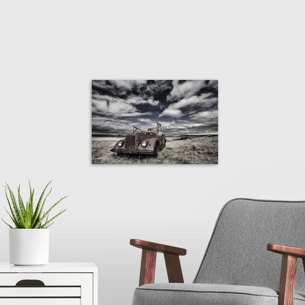 A modern room featuring A rusted, abandoned truck in a field in Iceland, under a cloudy sky.