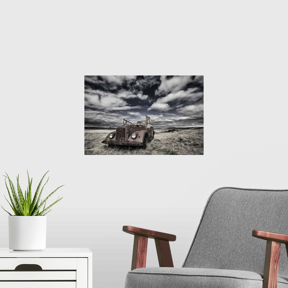 A modern room featuring A rusted, abandoned truck in a field in Iceland, under a cloudy sky.