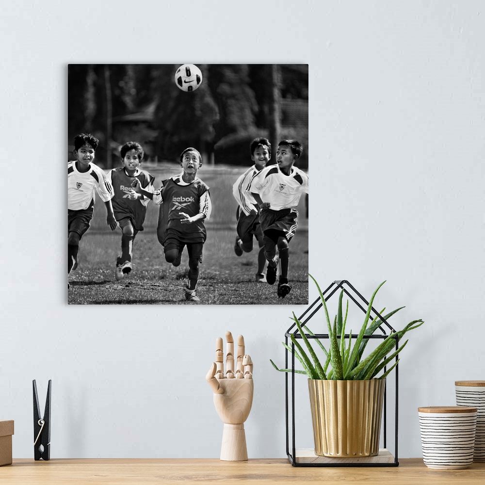 A bohemian room featuring A group of young boys playing soccer in a field, with the ball in the air.